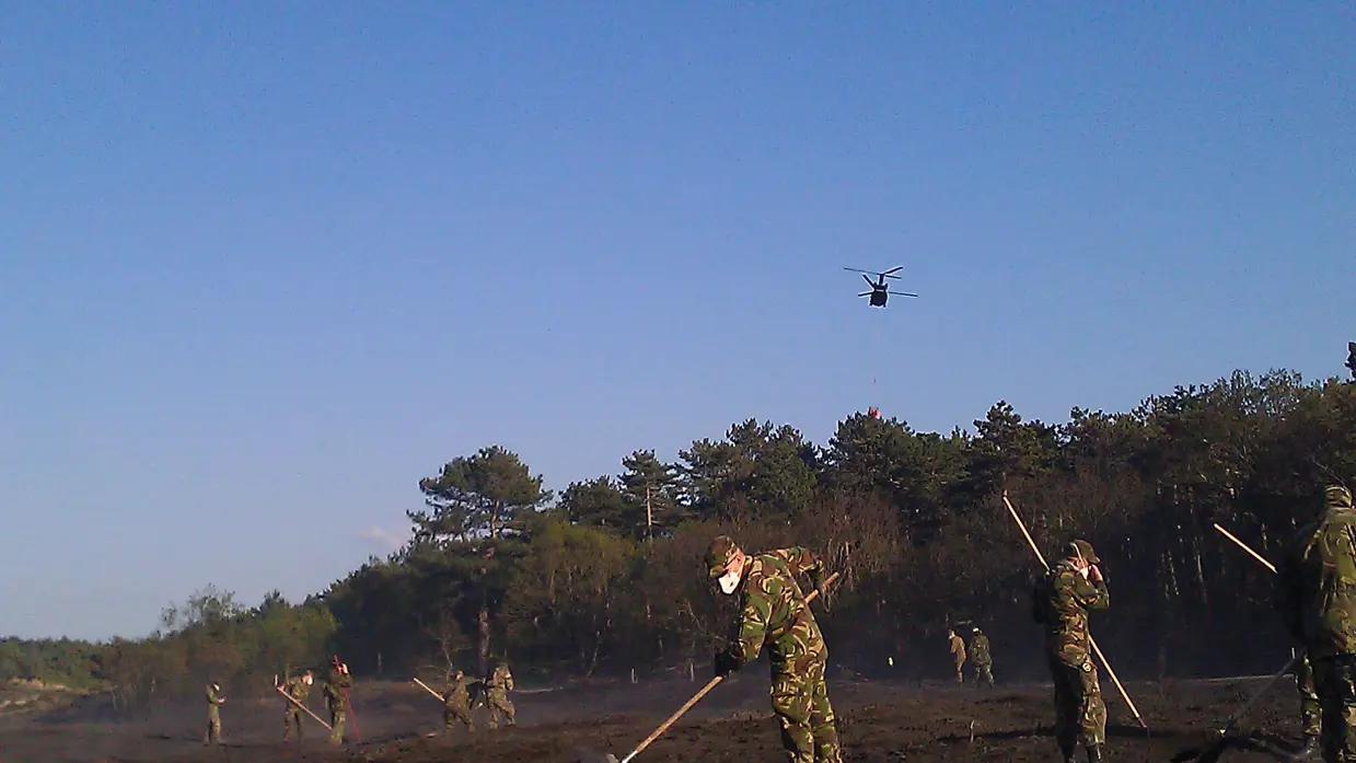 Landmachtmilitairen woelen met zwepen de besmeulde grond om.