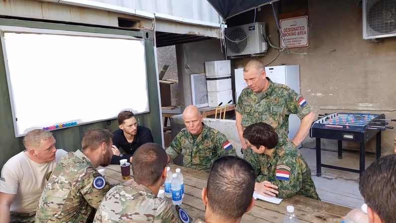 Militairen zitten aan een tafel en zijn met elkaar in gesprek.