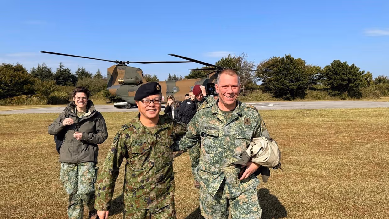 Twee militairen op de foto. Op de achtergrond een helikopter.