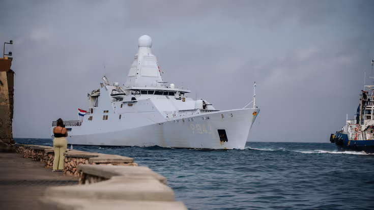 Marineschip vaart een baai binnen. 