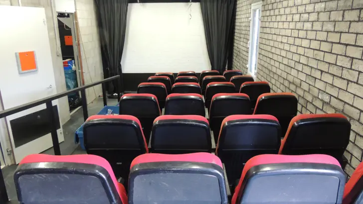 Zaal met bioscoopstoelen en een filmscherm.