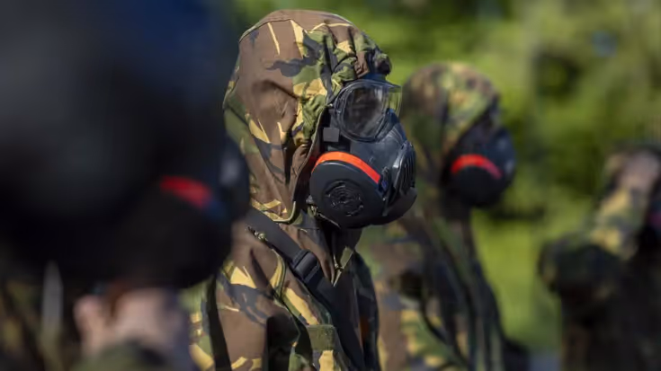 Een deelnemer aan de oefening met een gasmasker op het gezicht.