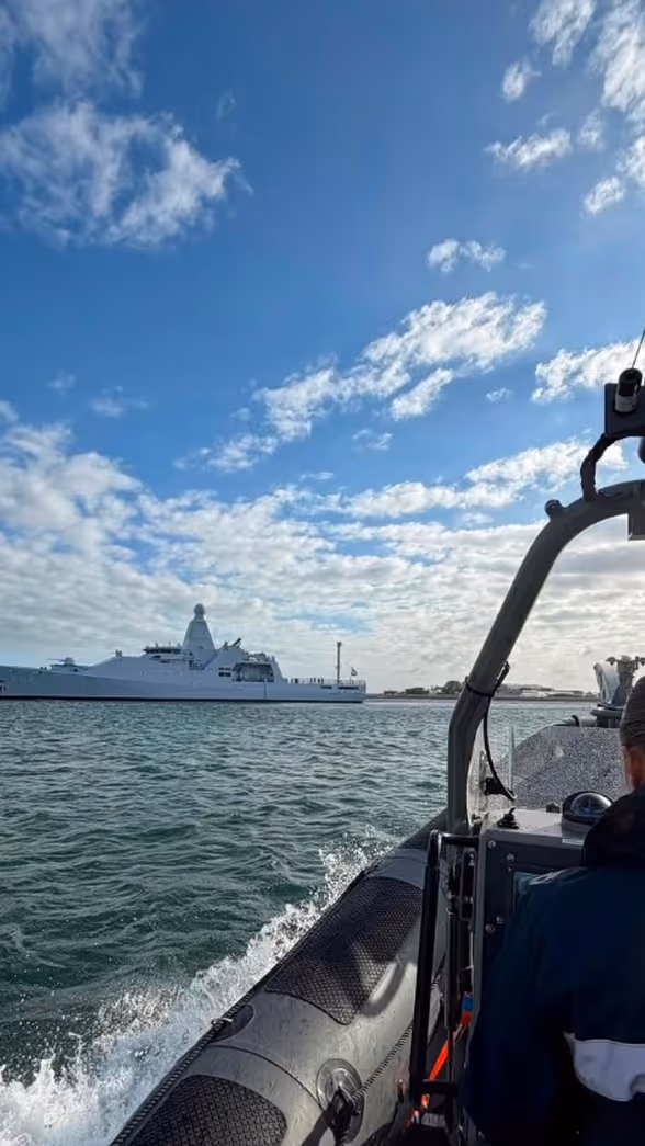Een marechaussee in een boot vaart richting een schip