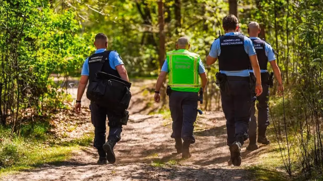 Vier marechaussees op de rug gezien, lopen door de natuur.