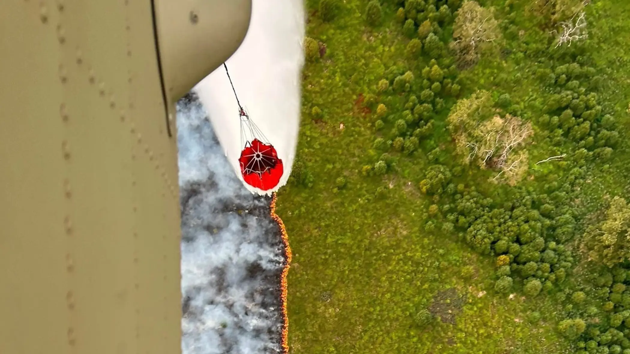 Een helikopter stort water op een brandend vuur