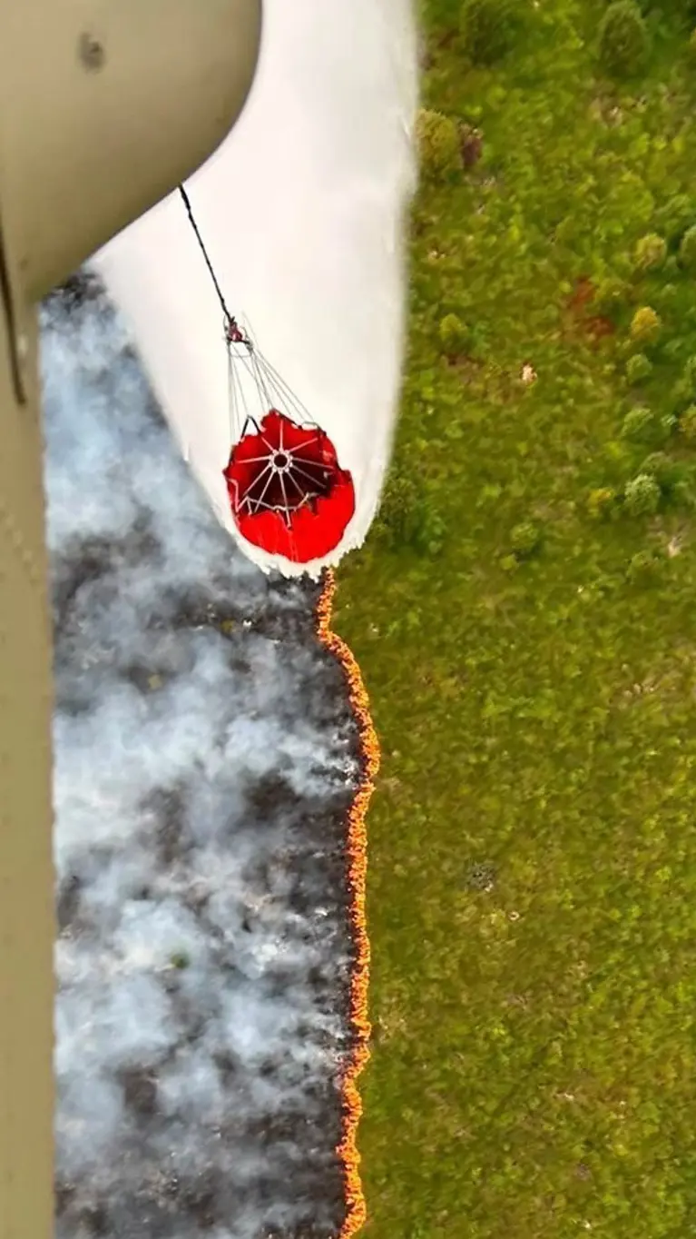 Een helikopter stort water op een brandend vuur