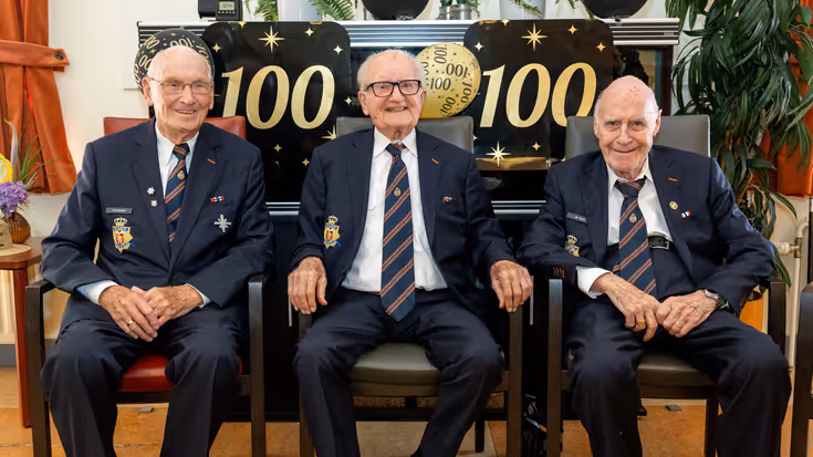 Drie 100-jarige veteranen zitten gemoedelijk naast elkaar.