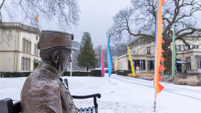 Bronbeker in de sneeuw, een bronzen beeld die een veteraan representeertop een bankje in het landgoed. 
