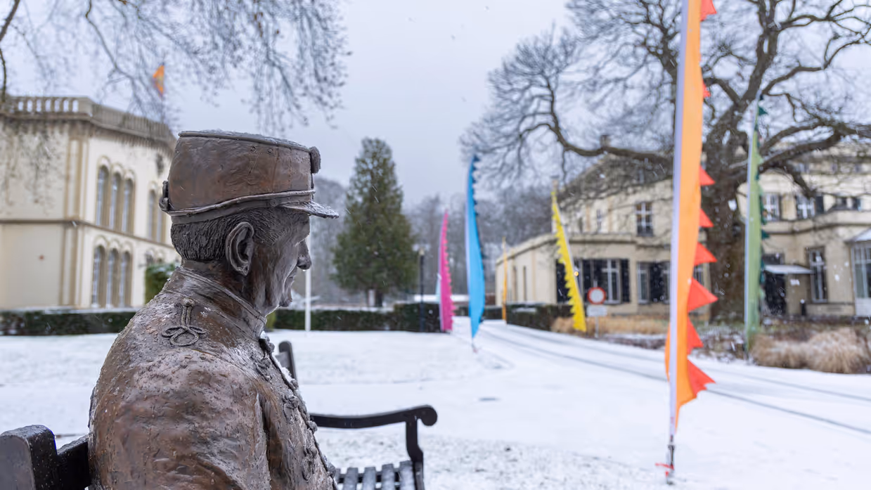 Bronbeker in de sneeuw, een bronzen beeld die een veteraan representeertop een bankje in het landgoed. 