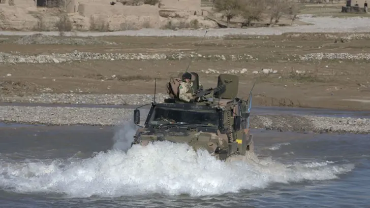 Bushmaster rijdt door het water.
