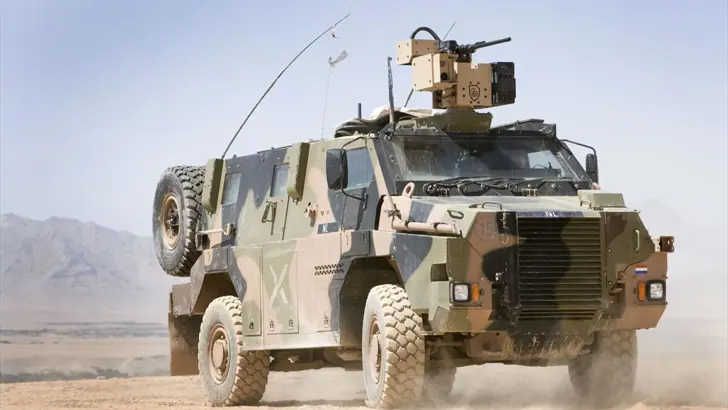 Bushmaster rijdt door het zand.