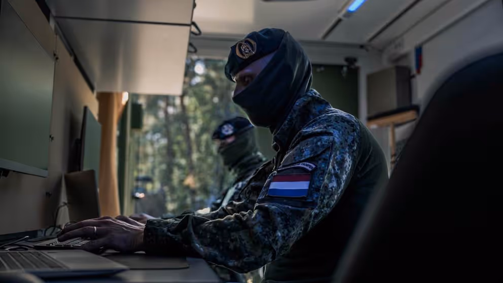 Onherkenbare militair zit achter een computer.