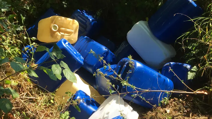 Plastic jerrycans in het gras.