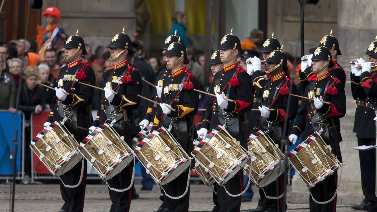 Tamboers en Pijpers spelen op straat.