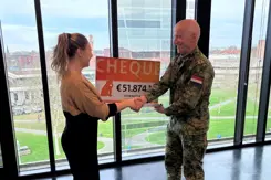 Militair overhandigt cheque van 51.874 euro aan vrouw.