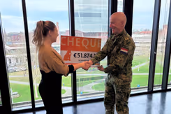 Militair overhandigt cheque van 51.874 euro aan vrouw.