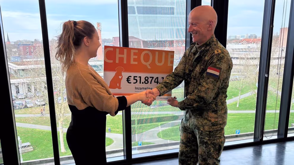 Militair overhandigt cheque van 51.874 euro aan vrouw.