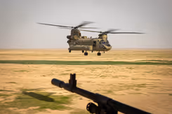 Chinook-transporthelikopter vlak boven de grond in woestijngebied. 