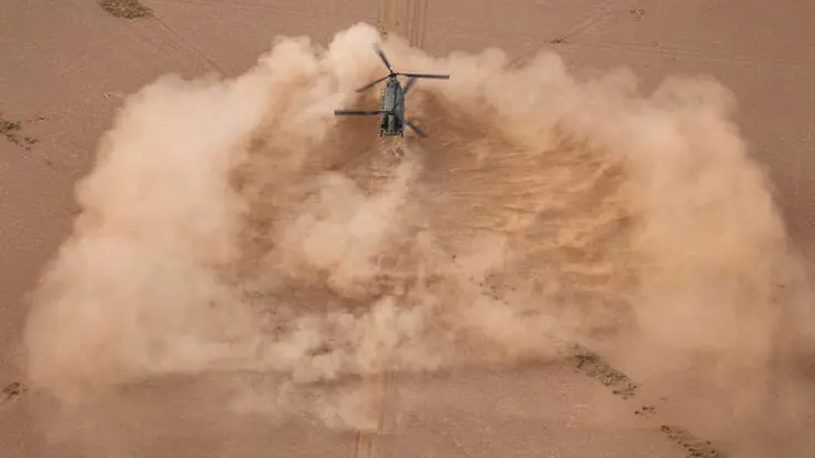 Een helikopter landt in de woestijn.