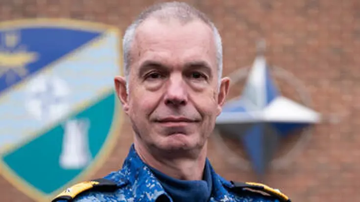 Portretfoto van commandeur Arjen Warnaar, met armen over elkaar in een blauw camouflage-uniform.