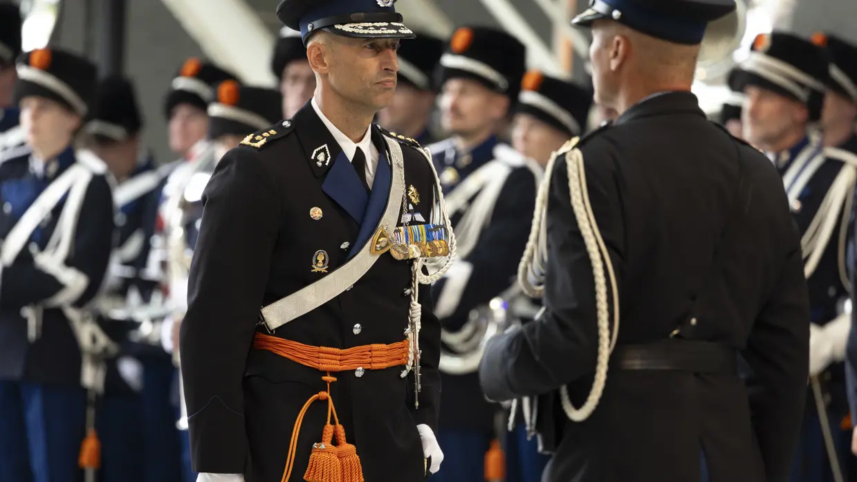 Costongs tijdens de ceremonie met militairen op de achtergrond. 