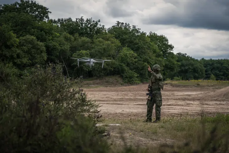 Een militair staat naast een zwevende drone.