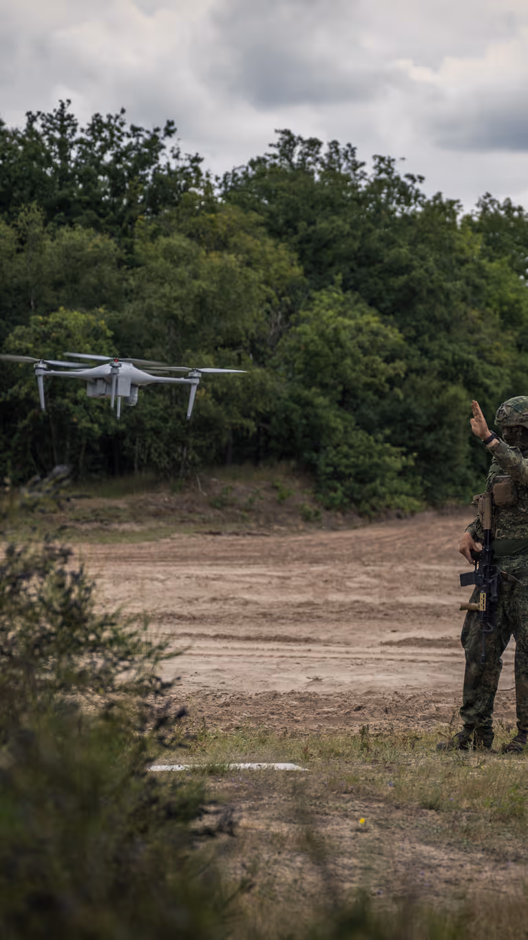 Een militair staat naast een zwevende drone.