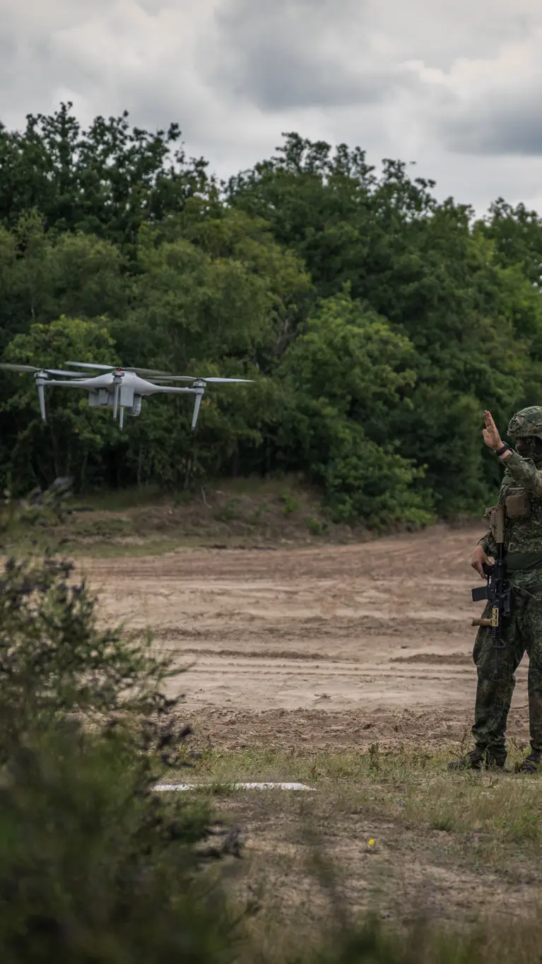 Een militair staat naast een zwevende drone.