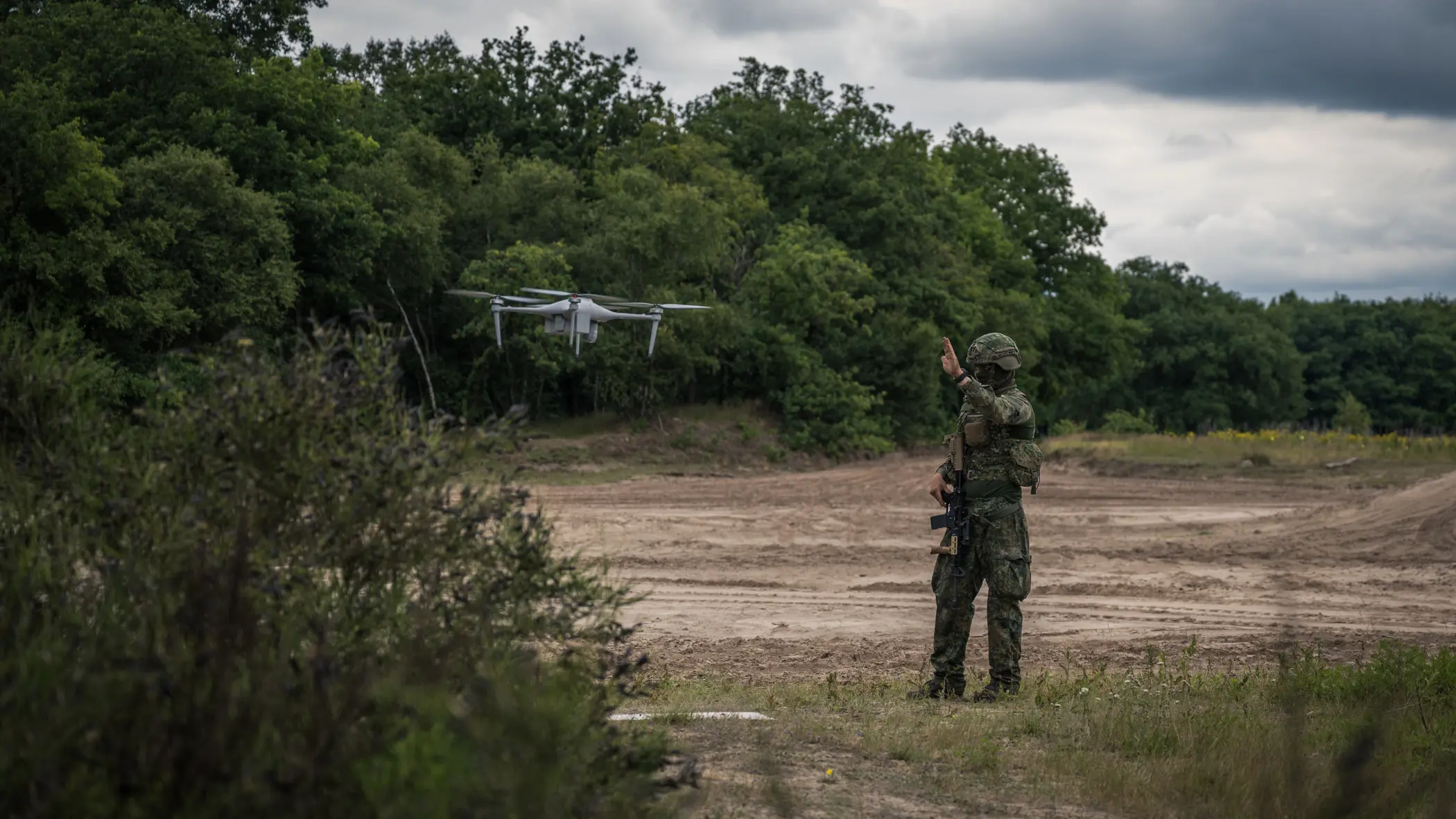 Een militair staat naast een zwevende drone.