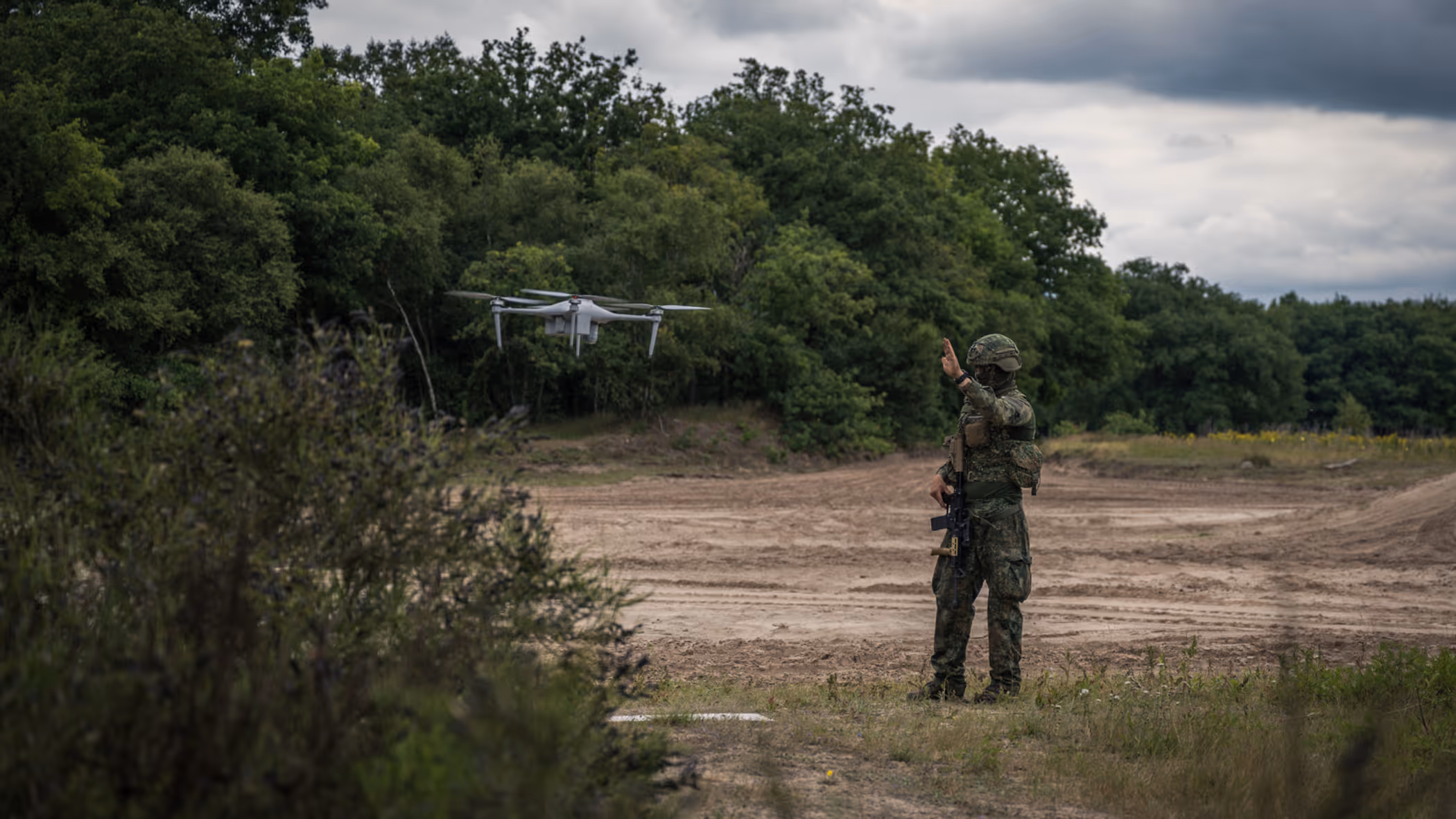 Een militair staat naast een zwevende drone.