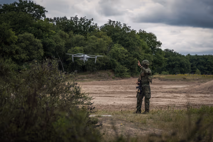 Een militair staat naast een zwevende drone.