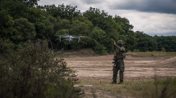 Een militair staat naast een zwevende drone.