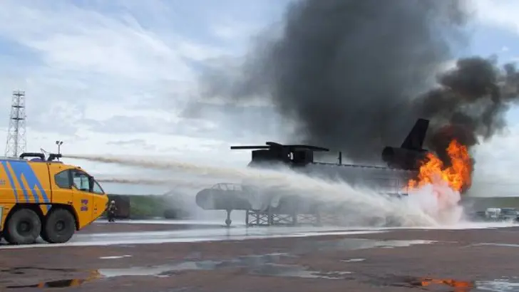 Crashtender blust met dakkanon een brand in een helikopter op een oefenterrein.