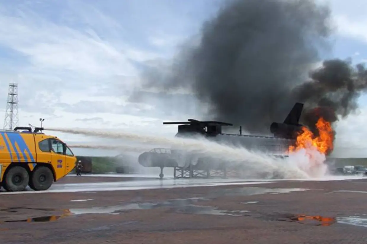 Crashtender blust met dakkanon een brand in een helikopter op een oefenterrein.