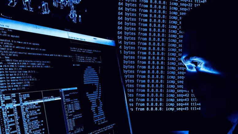 ICT’er in het donker achter computerscherm.