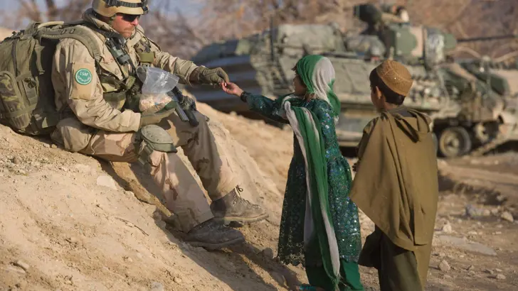 Militair deelt tijdens een patrouille snoep uit aan Afghaanse kinderen.
