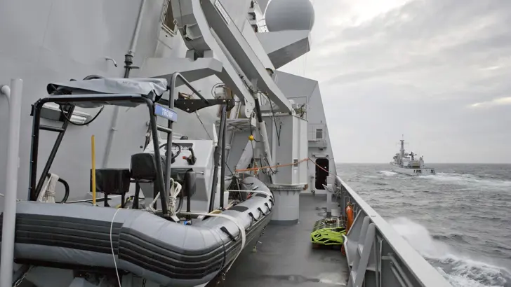 Een RHIB als bijboot aan boord van Zr.Ms. Tromp. Er achter de kraan die de boot in en uit het water takelt. Voor de Tromp vaart Zr.Ms. Van Speijk.