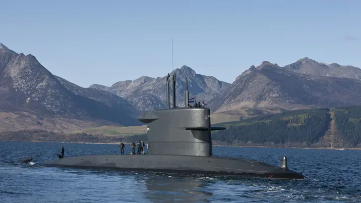 Onderzeeboot Zr.Ms. Bruinvis aan de oppervlakte, met bergen op de achtergrond.