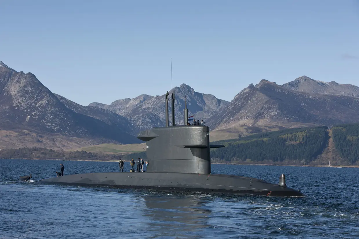 Onderzeeboot Zr.Ms. Bruinvis aan de oppervlakte, met bergen op de achtergrond.