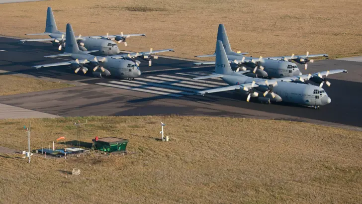 4 C-130 Hercules-transportvliegtuigen op een vliegbasis.