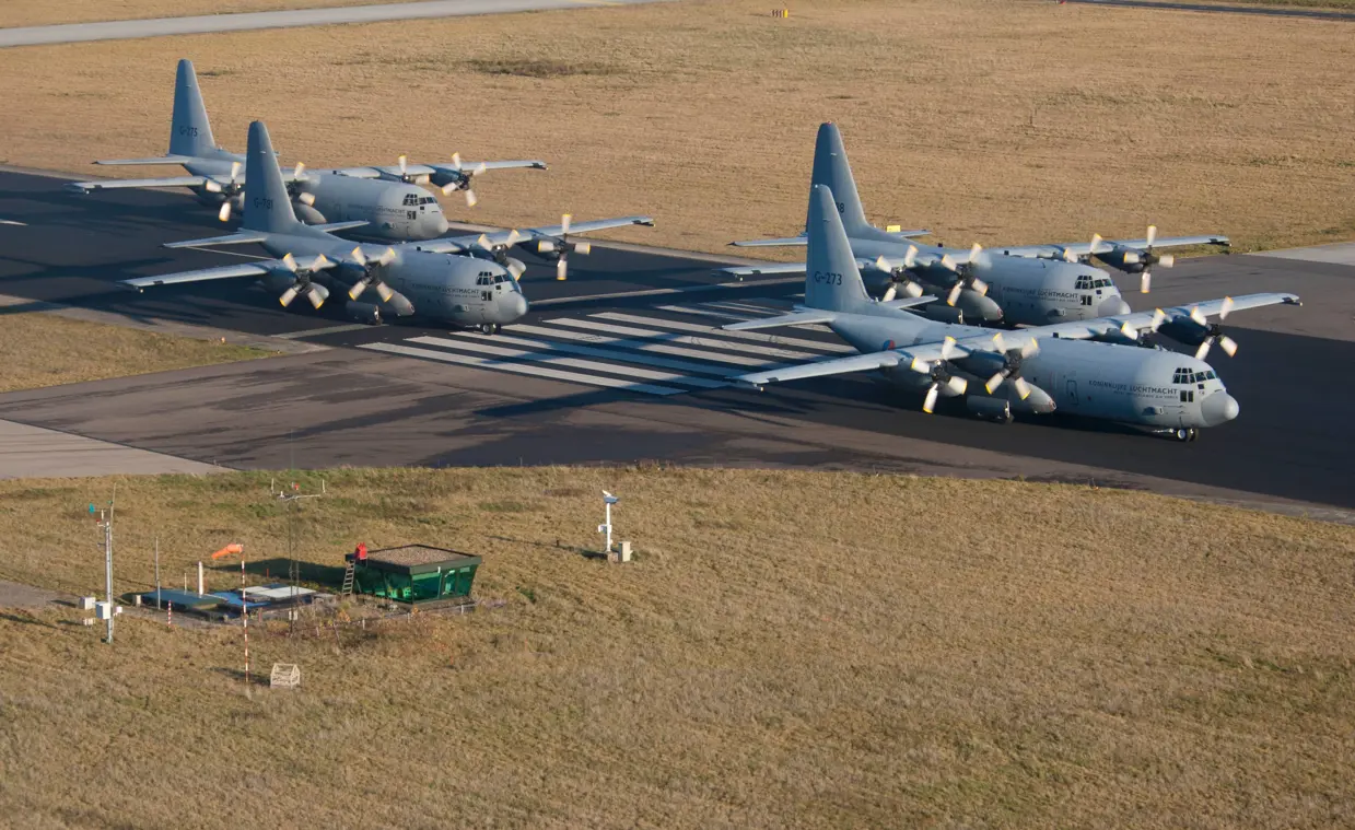 4 C-130 Hercules-transportvliegtuigen op een vliegbasis.