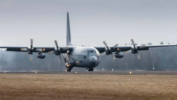 Een C-130 Hercules landt op een vliegbasis.