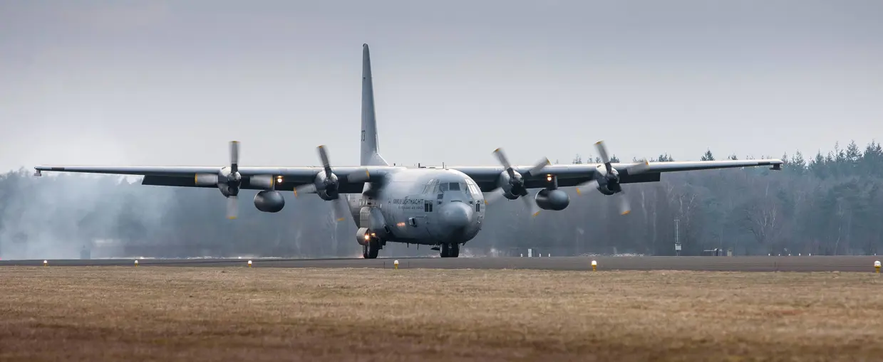Een C-130 Hercules landt op een vliegbasis.