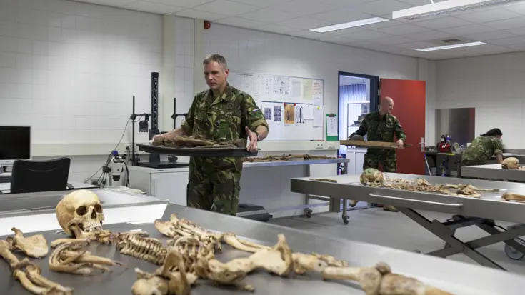 Medewerkers van de Bergings-en Identificatiedienst Koninklijke Landmacht dragen gevonden resten van onbekende soldaten het laboratorium in.