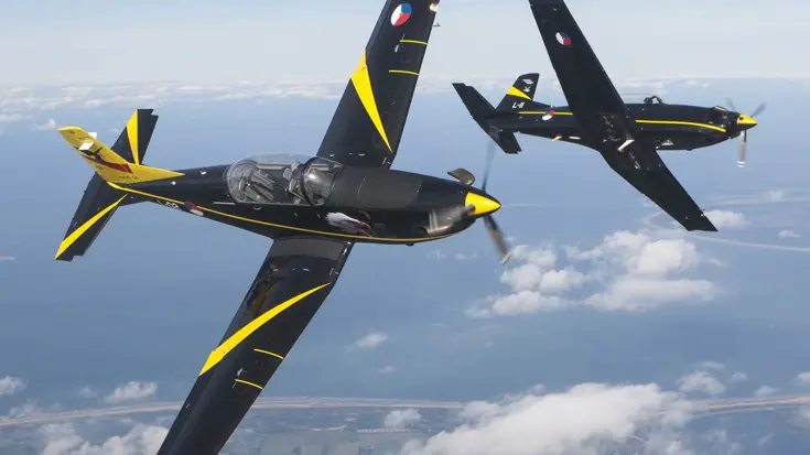 Twee Pilatus PC-7 vliegtuigen voeren een zij aan zij rol uit.
