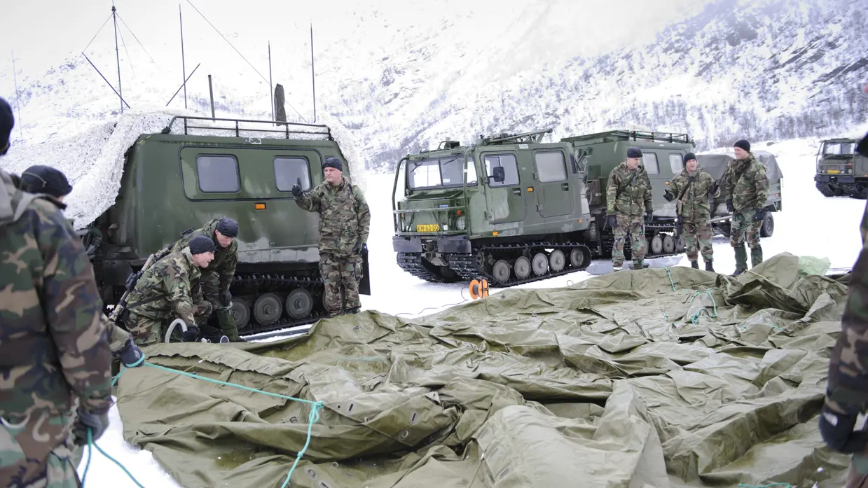 Mariniers zetten tent op in Noorwegen, omringd door Viking-voertuigen.