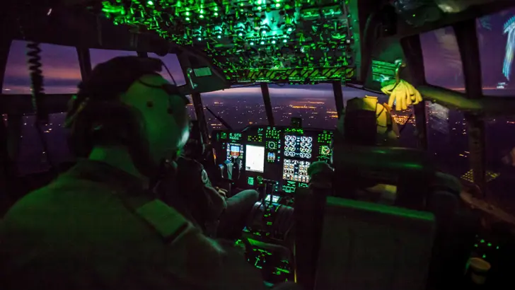 Cockpit met crew in een vliegtuig bij nacht.