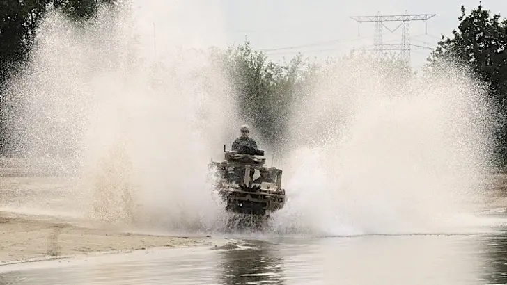 Water spat meters hoog op als een Vector door het water van een vijver rijdt.