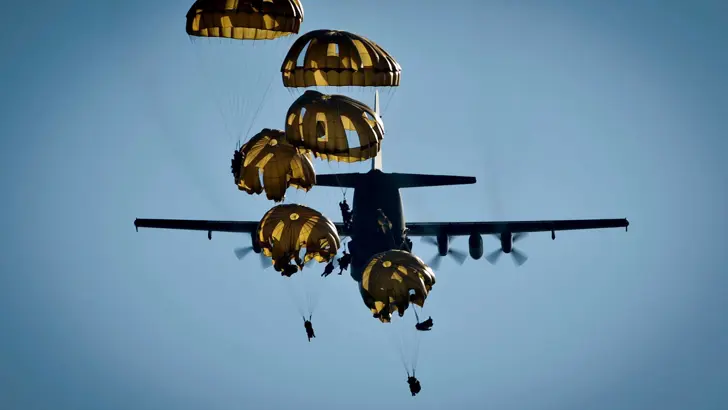 Parachutisten springen uit een C-130 Hercules.