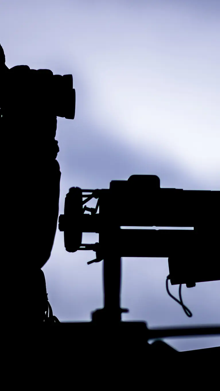 Het silhouet van een militair achter een mitrailleur. 